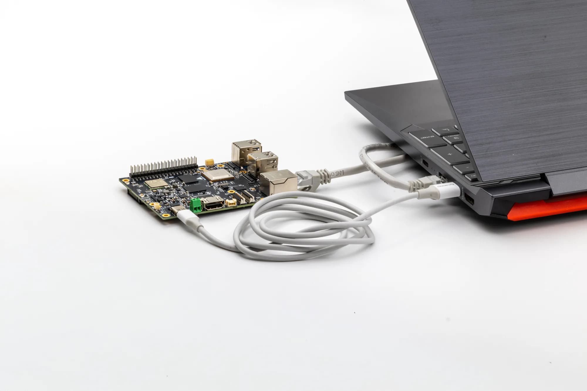 T3 Gemstone O1 geliştirme kartı, bir dizüstü bilgisayara seri konsol ve ethernet kablosuyla bağlanmış hâlde